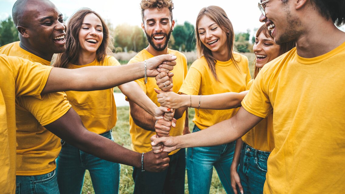 Multiracial happy young people stacking hands outside - Universi